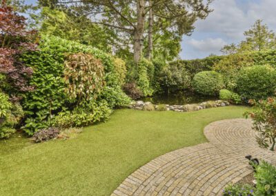 Curved block paving garden path with lawn and mature planting in Chilwell