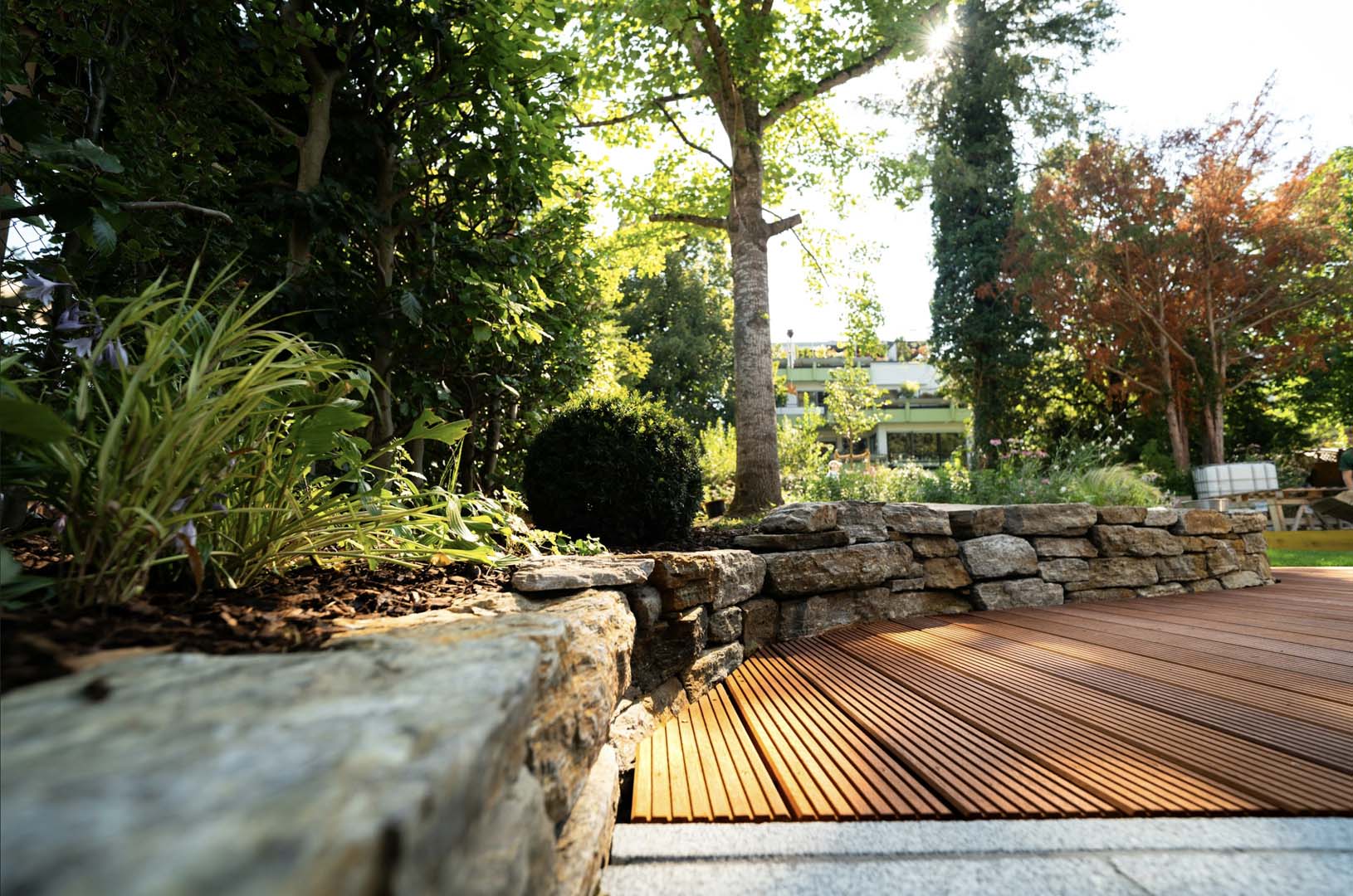 Garden maintenance in Aston-on-Trent with timber decking, stone retaining wall and mulched planting bed
